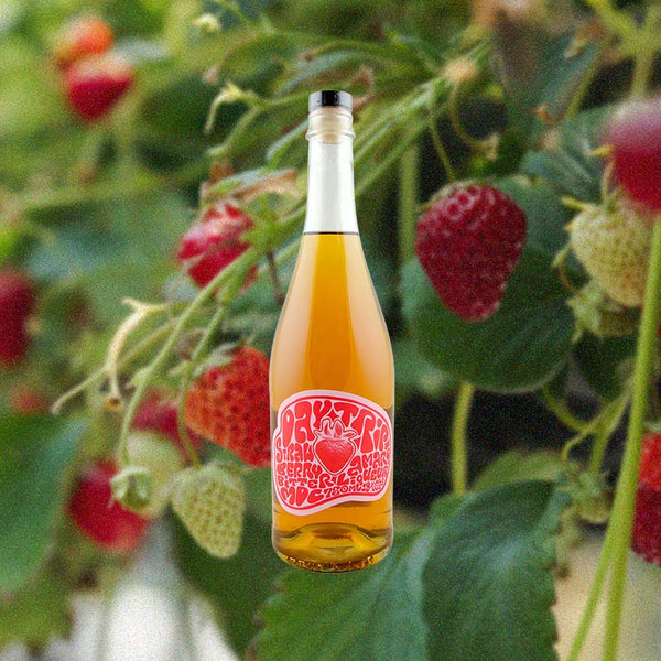 Bottle of Daytrip Strawberry Amaro over back drop of strawberry bushes.