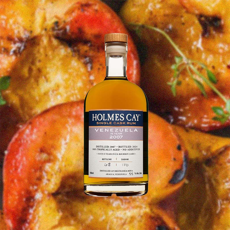 Bottle of Holmes Cay Venezuela 2007 15 Year Rum over back drop image of fruits.