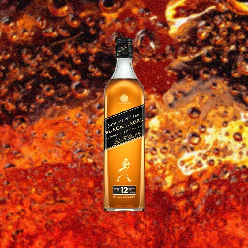 Bottle of Johnnie Walker Black Label over backdrop of orange liquid upclose.