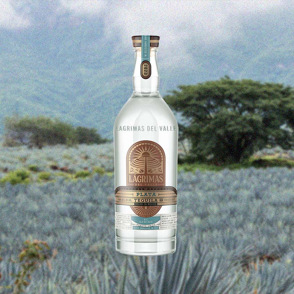 Bottle of Lágrimas del Valley 2023 El Sabino Plata Tequila over backdrop image of agave field in a valley.