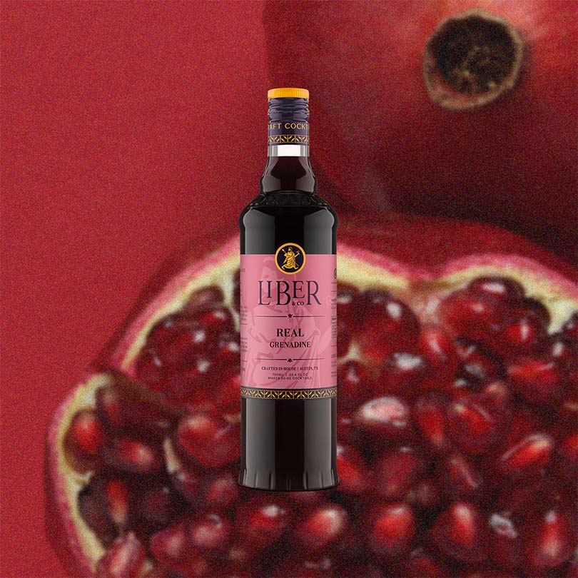 Bottle of Liber Real Grenadine with pomegranate background