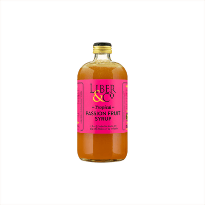 A large bottle of rich looking orange syrup with a fuschia label that reads: Liber & Co Tropical Passion Fruit Syrup. product image