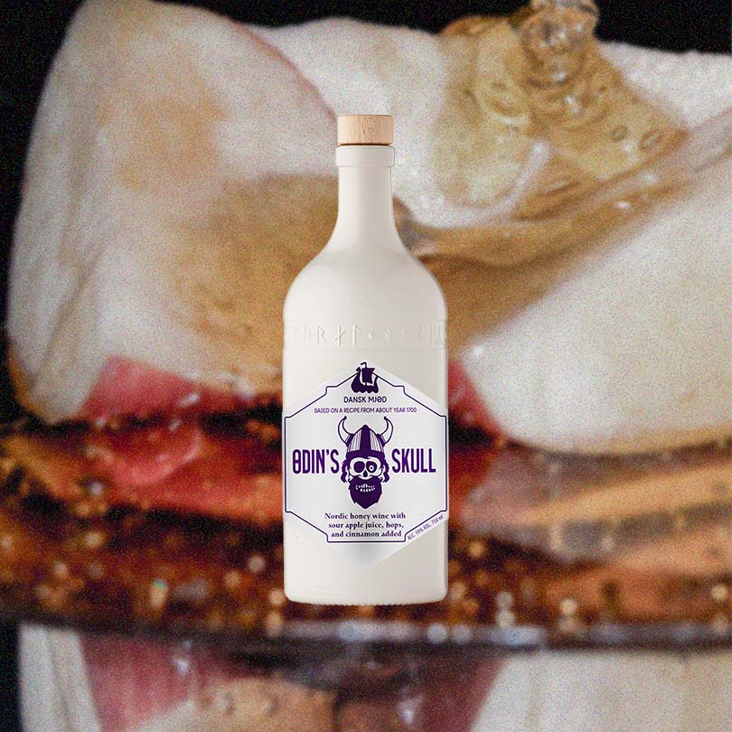 A bottle of Odin's Skull against a backdrop of apple slices drizzled with honey.