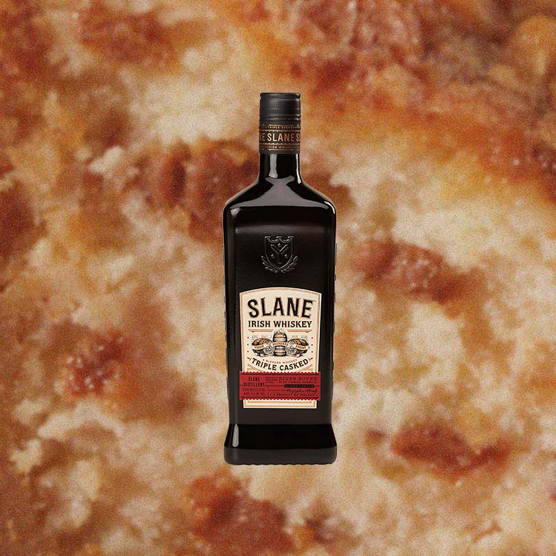 Bottle of Slane Triple Casked Irish Whiskey over backdrop of up close baked pastry.