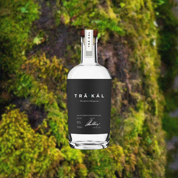 Bottle of TRÄKÁL Patagonian Spirit over backdrop image of green moss on a tree.