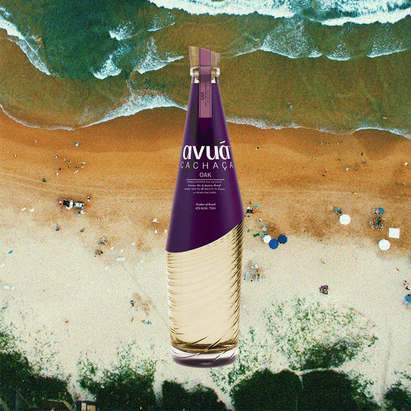 Bottle of Avua Oak Cachaca over background of beach