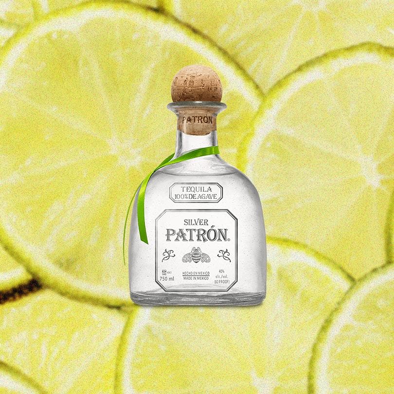 Bottle of Patron Silver Tequila over a backdrop of sliced limes.