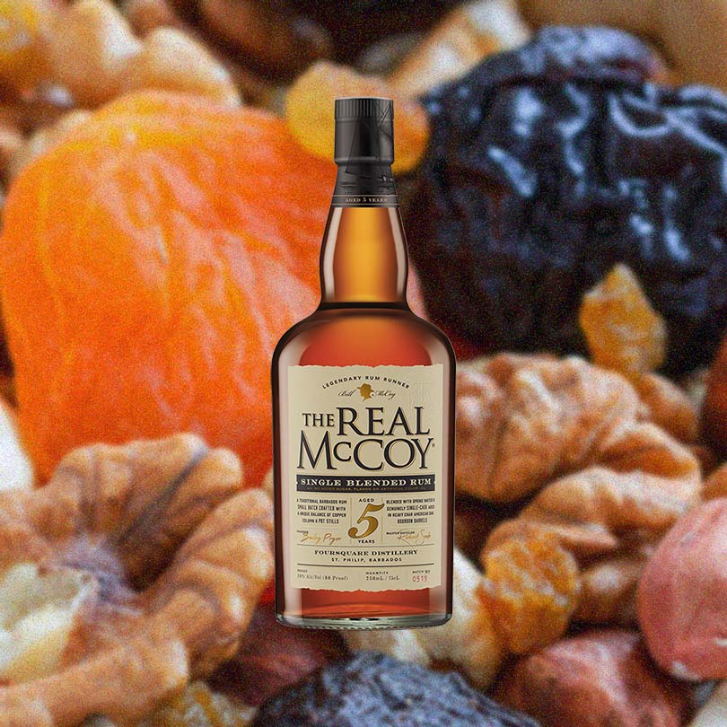 Bottle of The Real McCoy 5 Year Aged Rum over background image of fruits and nuts.