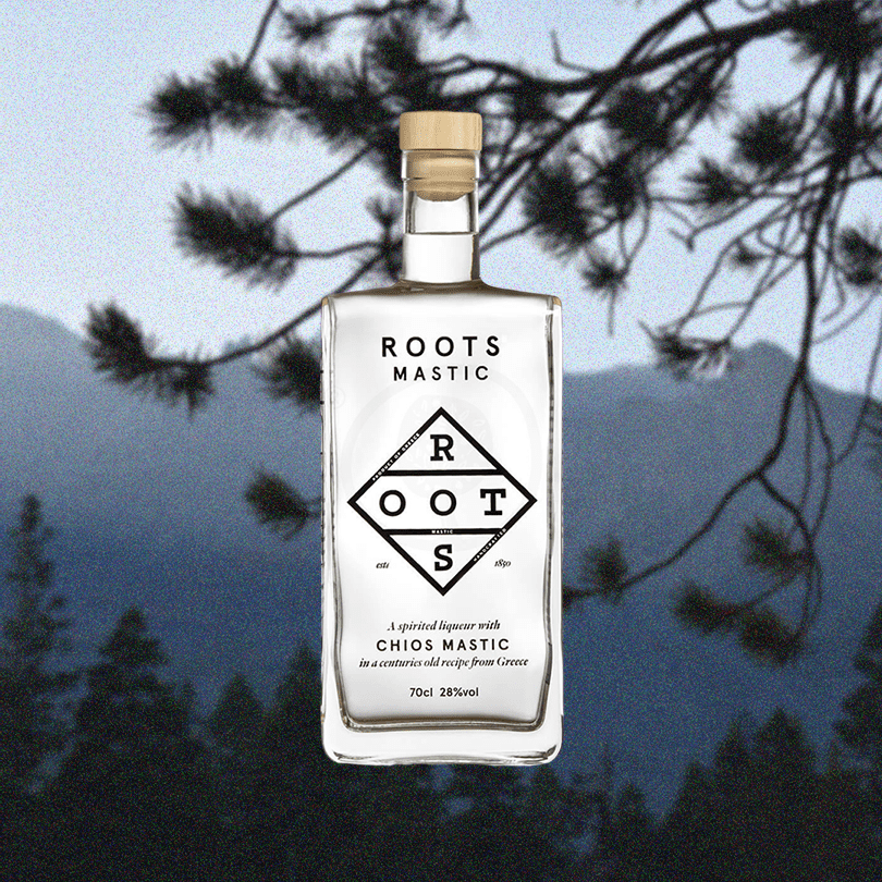 Bottle of Roots Chios Mastic Liqueur over a backdrop image of a pine tree and mountains.