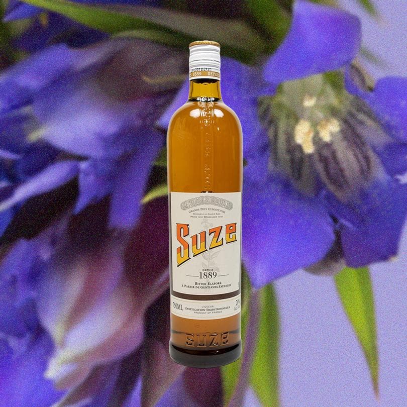 Bottle of Suze Aperitif over background of large purple flower.