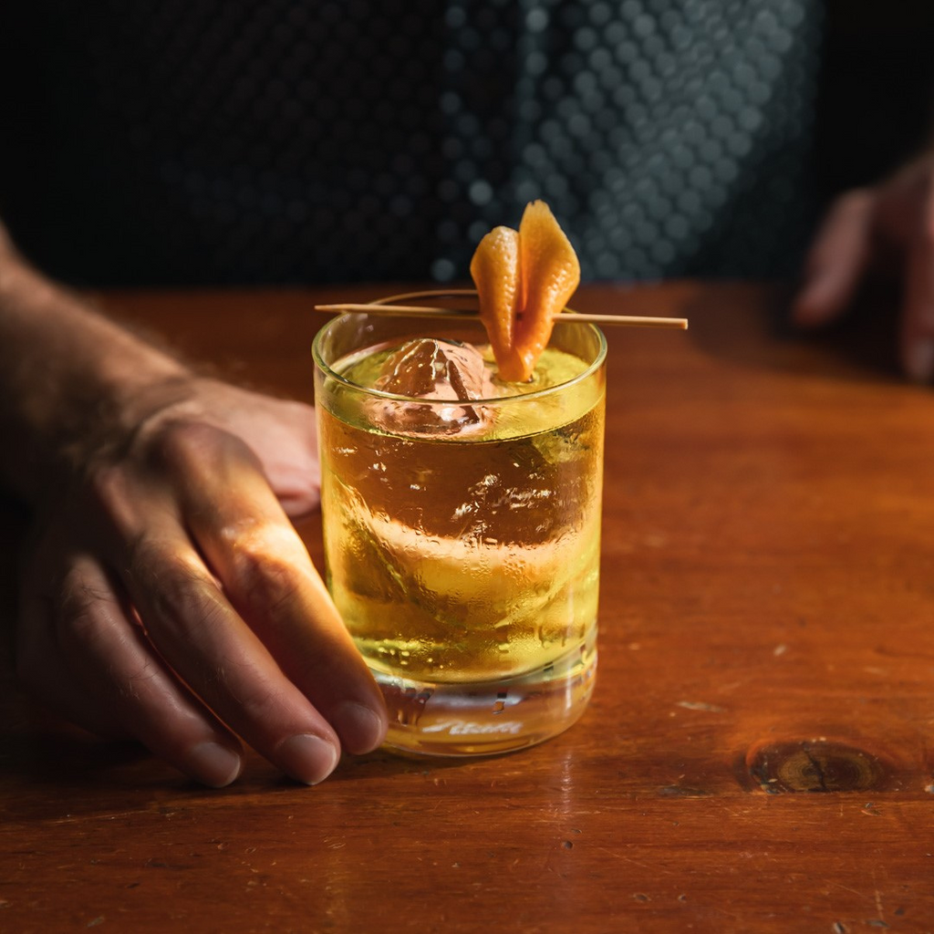 White Negroni cocktail placed on wooden table.