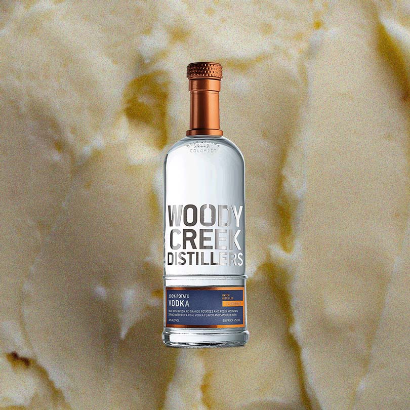 Bottle of Woody Creek Potato Vodka over backdrop of butter or vanilla.