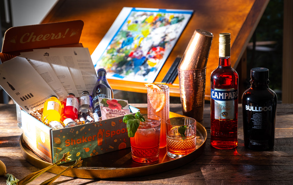Bottle of Campari + Bulldog Gin, alongside the Shaker and Spoon Negroni 2 boxset, and three beautiful cocktails.