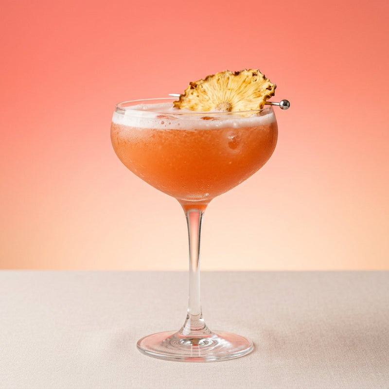 A photo of the Rum Negroni Blanc cocktail containing Planteray 3 Stars White Rum, Campari Aperitivo, Fresh pressed pineapple juice, Freshly squeezed lime juice, Giffard Sugar Cane Syrup (Sirop Sucre de Canne), Salt in a Coupe.