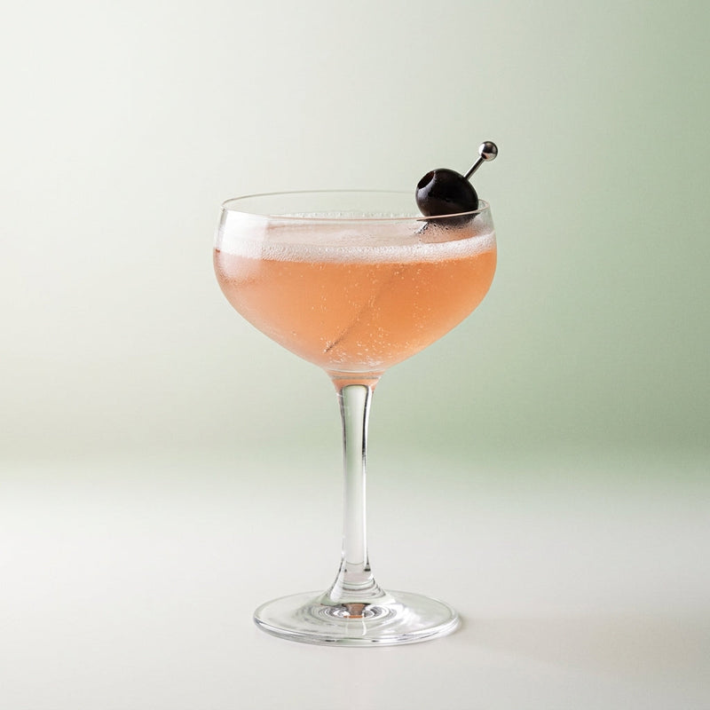 A photo of the Rum Riviera Fizz cocktail containing Basil leaves, Planteray 3 Stars White Rum, Freshly squeezed lemon juice, Giffard Sugar Cane Syrup (Sirop Sucre de Canne), Campari Aperitivo, Perrier Jouet Grand Brut Champagne in a Coupe.