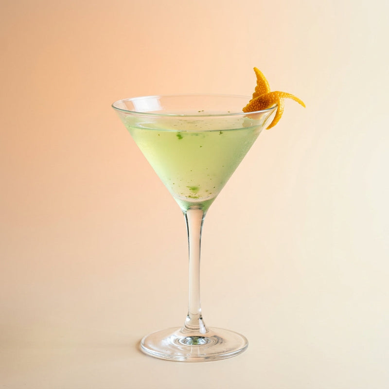 A photo of the The Orange Grove Martini cocktail containing Mint leaves, Beefeater London Dry Gin, Giffard Sugar Cane Syrup (Sirop Sucre de Canne), Angostura Orange Bitters in a Martini.