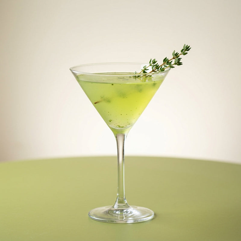 A photo of the Basil & Thyme Martini cocktail containing Basil leaves, Ketel One Vodka, Freshly squeezed lime juice, Giffard Sugar Cane Syrup (Sirop Sucre de Canne), Chilled water in a Martini.