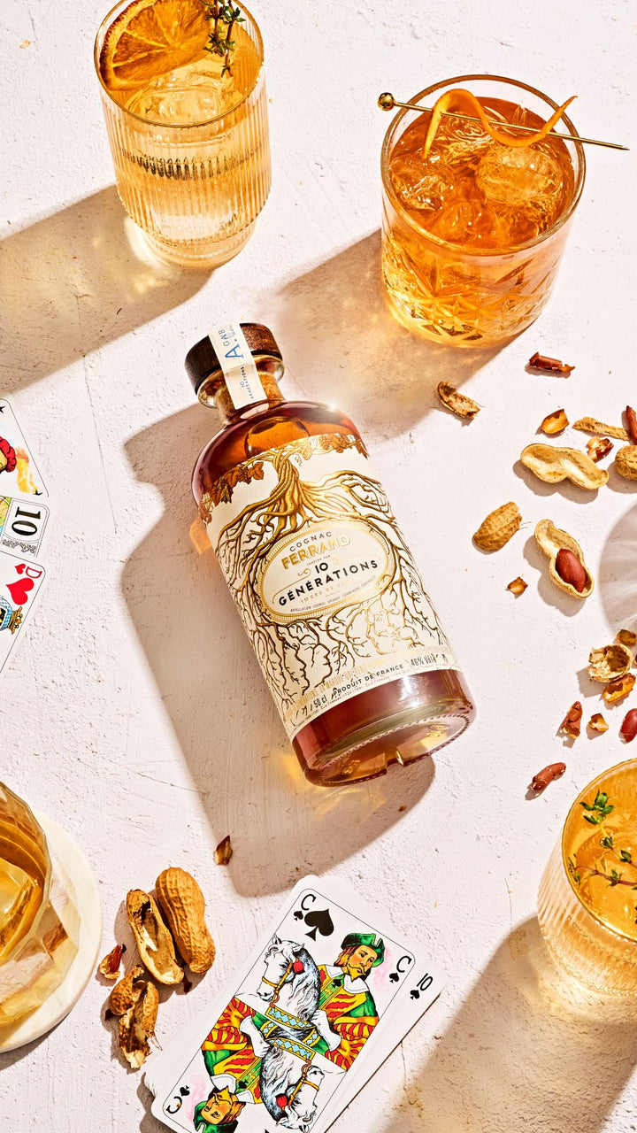 Bottle of 'Duchess' gin with two cocktails and playing cards on a light surface