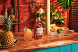 Bottle of Planteray rum on a wooden bar with a cocktail and garnishes.