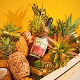 Bottle of Planteray Stiggin's Fancy Rum surrounded by pineapples and decorative items on a yellow background