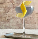 Cocktail in a glass with a lemon twist on a textured surface