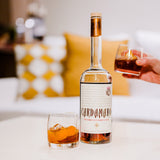 Bottle of Cardamaro with two glasses on a table, blurred background