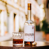 Bottle of Cardamamo liqueur with a glass on a wooden surface, blurred background