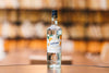 A bottle of Giffard Triple Sec in sharp focus with a blurred background in colors of orange and warm brown..