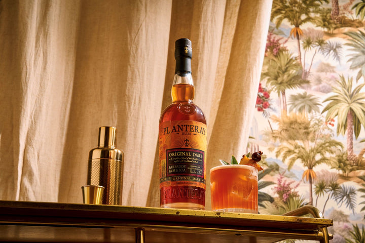 Bottle of Planteray rum on a bar with a tropical-themed background