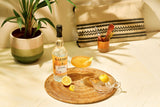 Cocktail with a bottle of Planteray 3 Star Rum on a woven coaster with a lemon wedge.