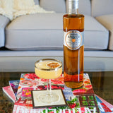 Bottle of Rothman & Winter Orchard Apricot Liqueur with a cocktail on a colorful tablecloth.