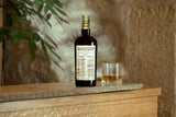 Hampden rum bottle and glasses on a wooden surface with a stone wall background