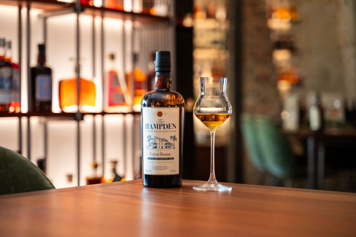 Bottle of Hampden rum on a bar counter with a glass of whisky.