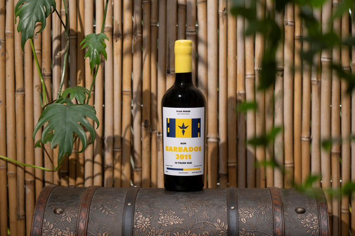 Bottle of rum with a yellow cap on a decorative barrel against a bamboo background