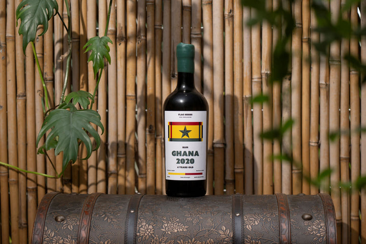 Wine bottle with Ghana 2020 label on a decorative barrel against a bamboo background