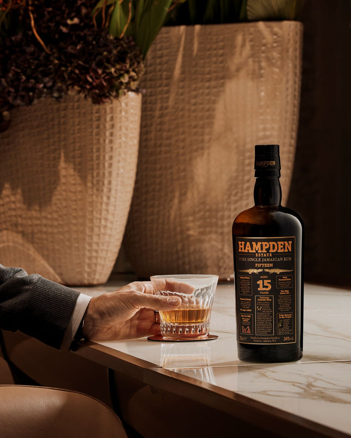 Hampden 15-year-old rum bottle with a glass of rum on a table.