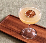 Cocktail in a glass with a lime wheel on a wooden tray