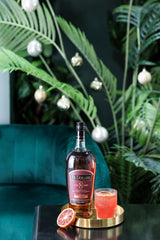 Bottle of El Dorado rum with a cocktail on a table with greenery in the background