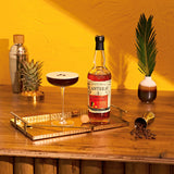 Bottle of Planteray Stiggin's Fancy Rum on a wooden table with a drink and decorative elements.