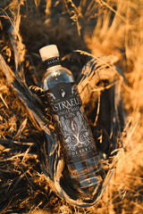 A bottle of Astraeus gin in a woven basket with grass in the background
