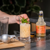 Cocktail being prepared with a bottle of Liber syrup on a bar counter.