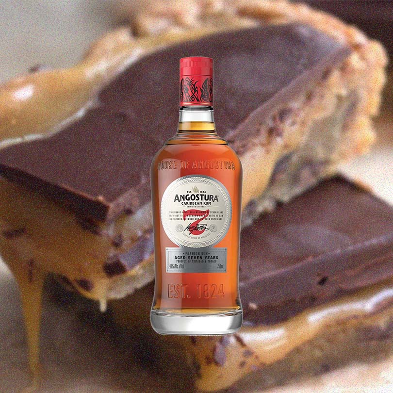 Bottle of Angostura 7 Year Old Rum over back drop of chocolate baked goods.