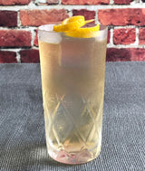 Cocktail with lemon twist in a glass against a brick wall background