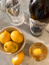 Bottle of Baldoria beer with a glass of beer and lemons on a marble surface
