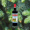 A tall bottle with a red cap reading: Braulio Bormio Amaro Alpino with a hand drawn image of the Alps against a backdrop of green spruce boughs