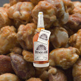 Bottle of Brother’s Bond Straight Bourbon Whiskey over back drop of candied nuts.