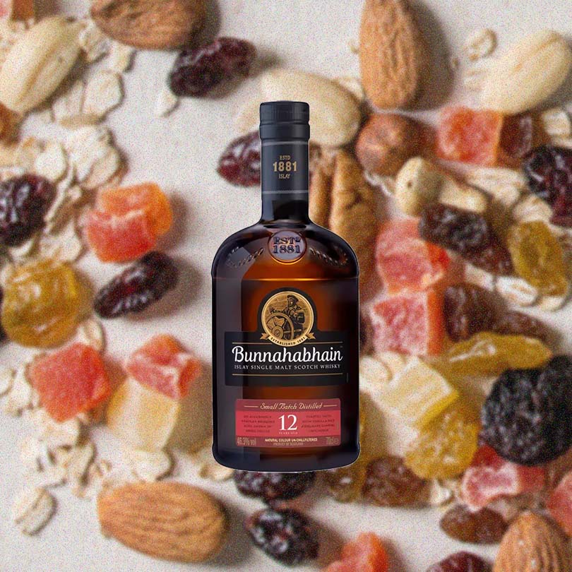 Bottle of Bunnahabhain 12 Year Islay Single Malt Scotch Whisky over back drop of nuts and fruit.