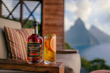 Bottle of Chairman's Reserve Spiced Rum behind a high ball cocktail outdoors.