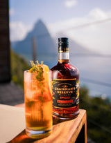 Bottle of Chairman's Reserve Spiced Rum behind a high ball cocktail outdoors.