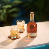 Bottle of Canerock rum with two glasses on a table outdoors.